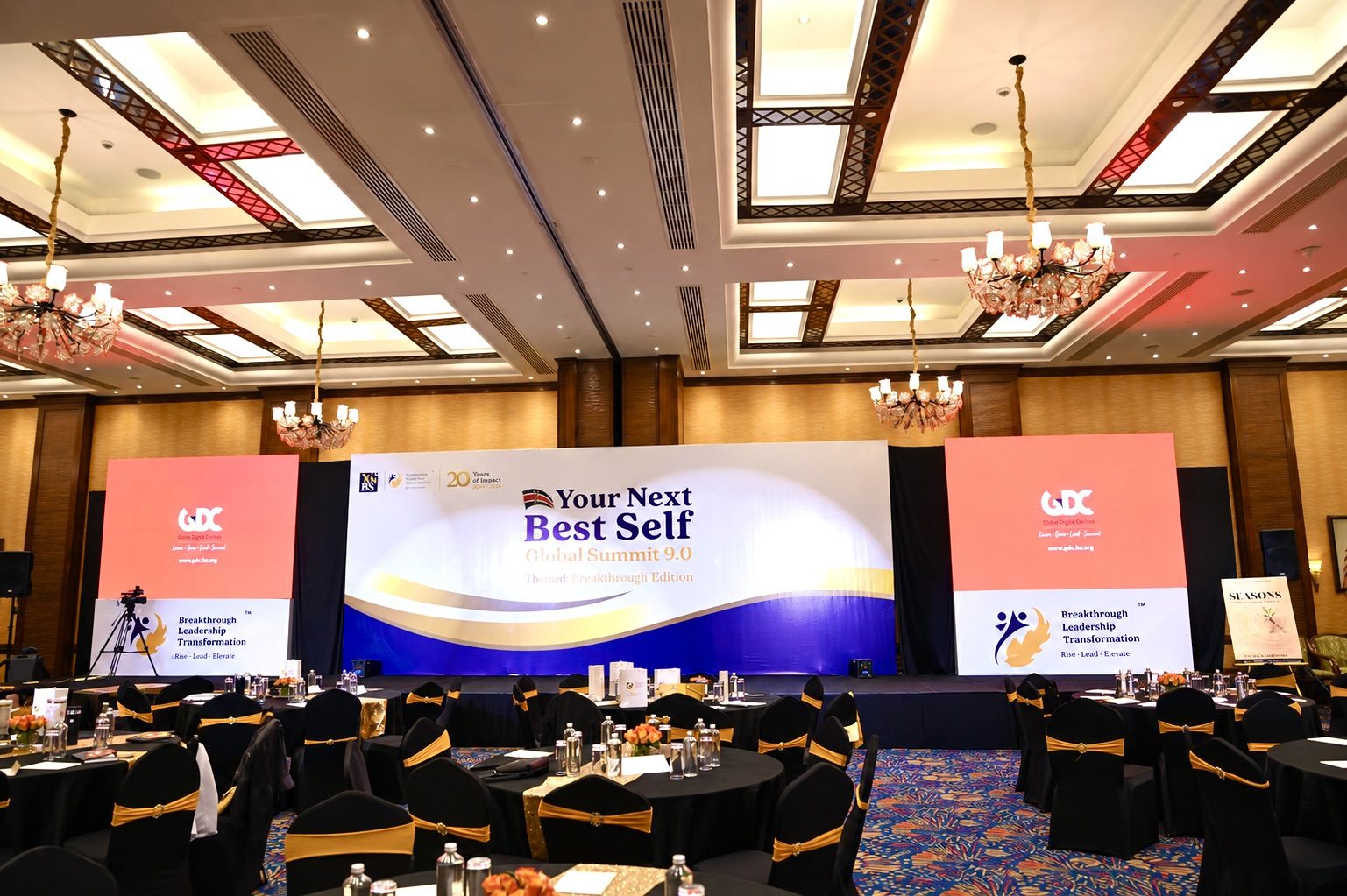 BLT summit stage with branded screens and roundtable seating