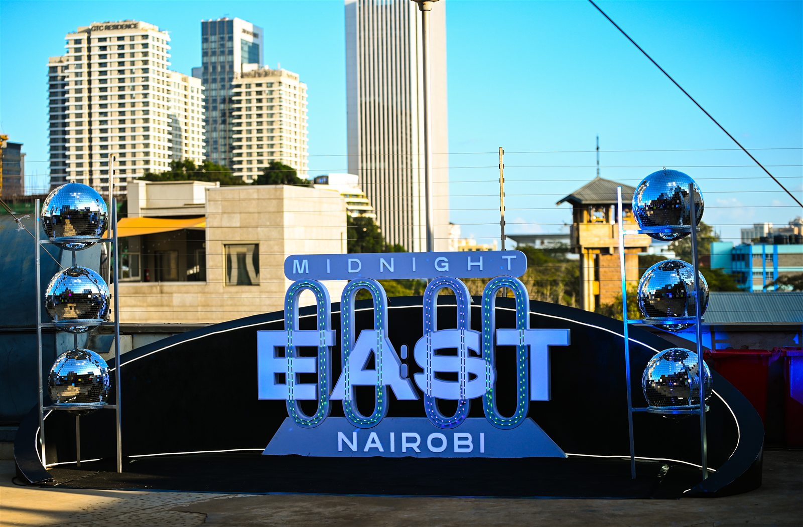 Midnight East Nairobi event sign with disco balls against the city skyline